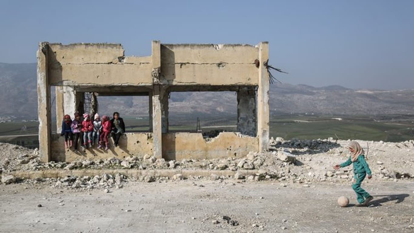 Kinder spielen in den Trümmern einer zerstörten Schule.