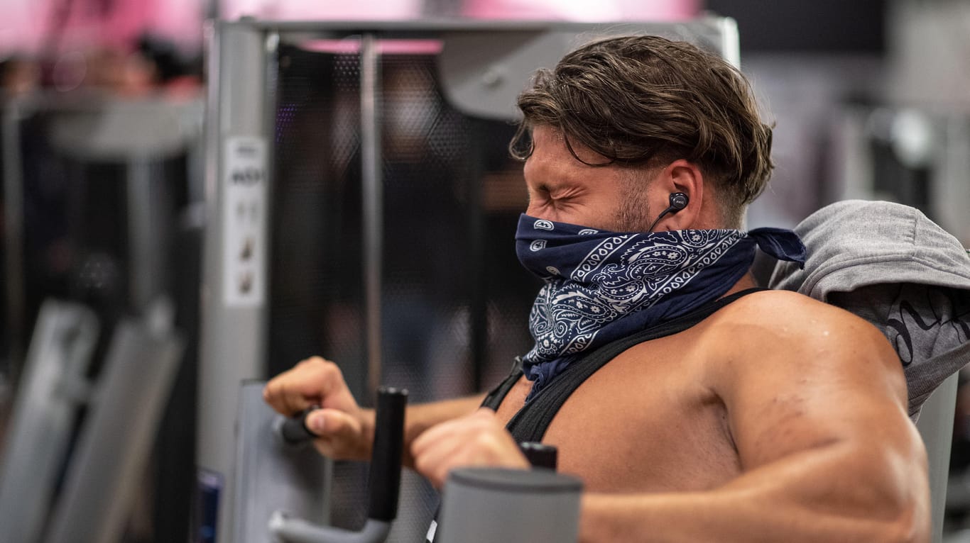 Ein Mann mit Mundschutz trainiert in einem Fitnessstudio der Kette McFit an einer Brustpresse: Unter Corona-Auflagen kann dort wieder trainiert werden.