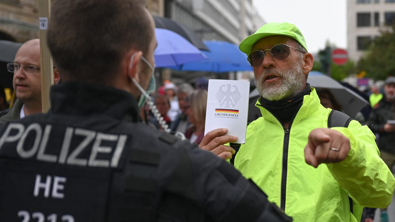 Ein Mann hält einem Polizeibeamten während einer Demonstration in Frankfurt eine Ausgabe des Grundgesetzes entgegen: Mehr als 500 Menschen haben in der Innenstadt protestiert.