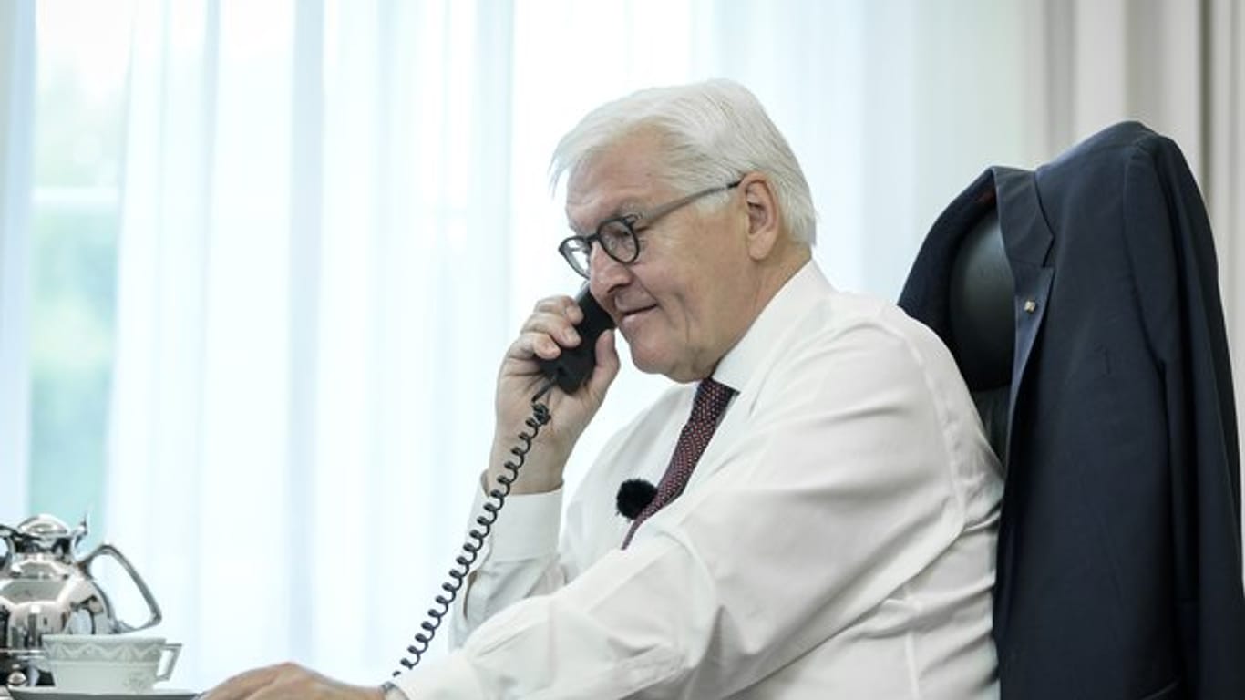 Bundespräsident Frank-Walter Steinmeier telefoniert an seinem Schreibtisch mit der Bewohnerin eines Altenheims in Bremen.