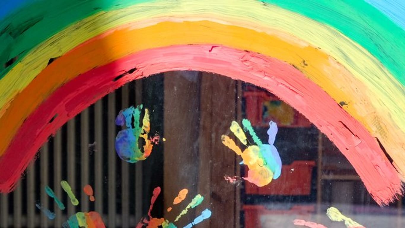 Kinderhände und ein Regenbogen an einer Kita: Die Betreuung in der Corona-Krise soll ausgeweitet werden.