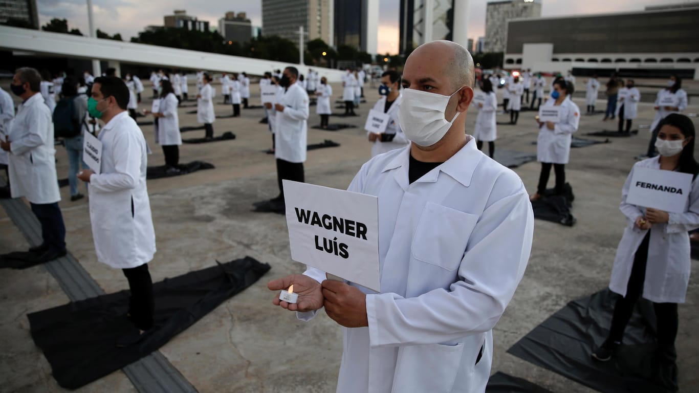 Protest von Pflegern in Brasilia: Mit kerzen und Schildern in den Händen erinnern sie an Mediziner, die im Einsatz während der Pandemie verstorben sind.