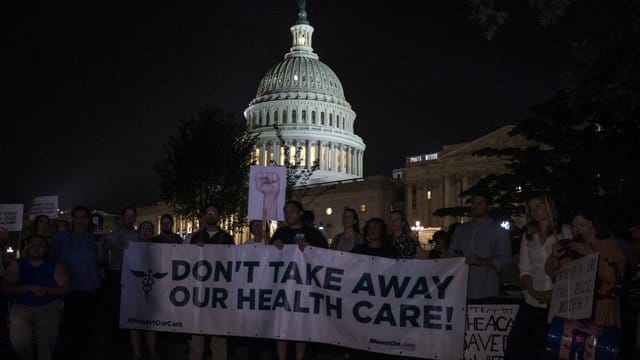 Demonstranten halten 2017 vor dem Kapitol in Washington ein Banner mit der Aufschrift "Don't take away our health care!" (Nehmt uns nicht unsere Krankenversicherung weg!) hoch. Demonstranten halten 2017 vor dem Kapitol in Washington ein Banner mit der Aufschrift "Don't take away our health care!" (Nehmt uns nicht unsere Krankenversicherung weg!) hoch.