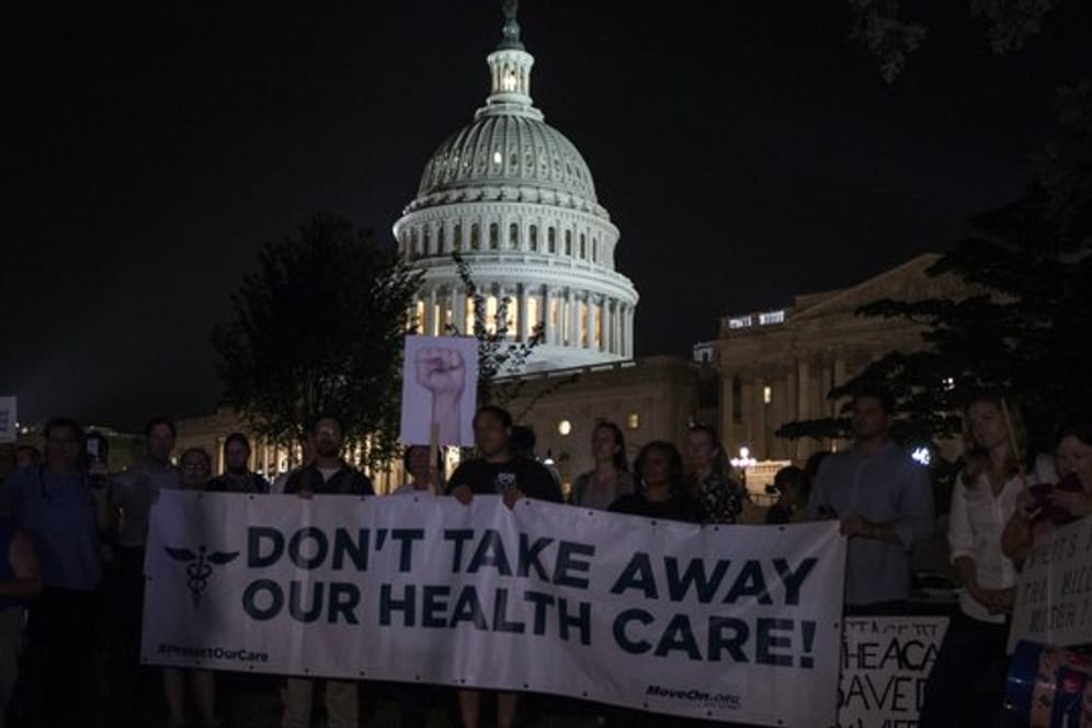 Demonstranten halten 2017 vor dem Kapitol in Washington ein Banner mit der Aufschrift "Don't take away our health care!" (Nehmt uns nicht unsere Krankenversicherung weg!) hoch.