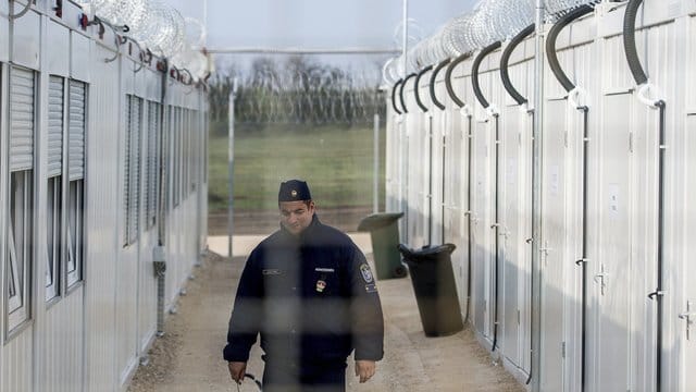 Ein ungarischer Polizist patrouilliert durch ein Lager für Asylsuchende an der Grenze zu Serbien. Ein ungarischer Polizist patrouilliert durch ein Lager für Asylsuchende an der Grenze zu Serbien.