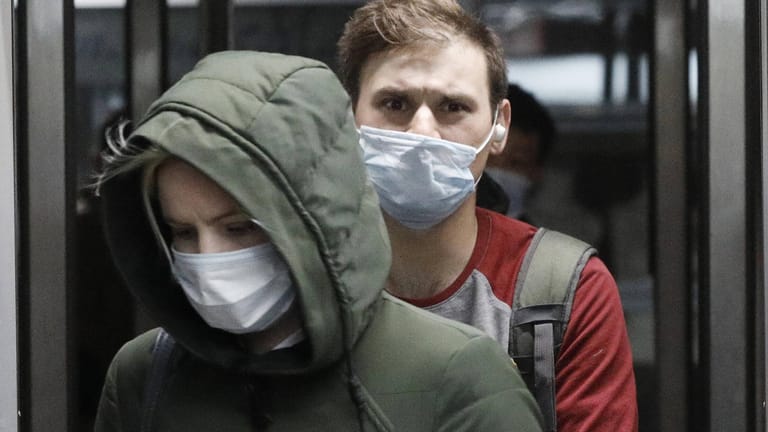 Zwei junge Menschen tragen Schutzmasken: Wenn das Coronavirus über Mikrotröpfchen beim Sprechen übertragen wird, sind diese Masken umso wichtiger.