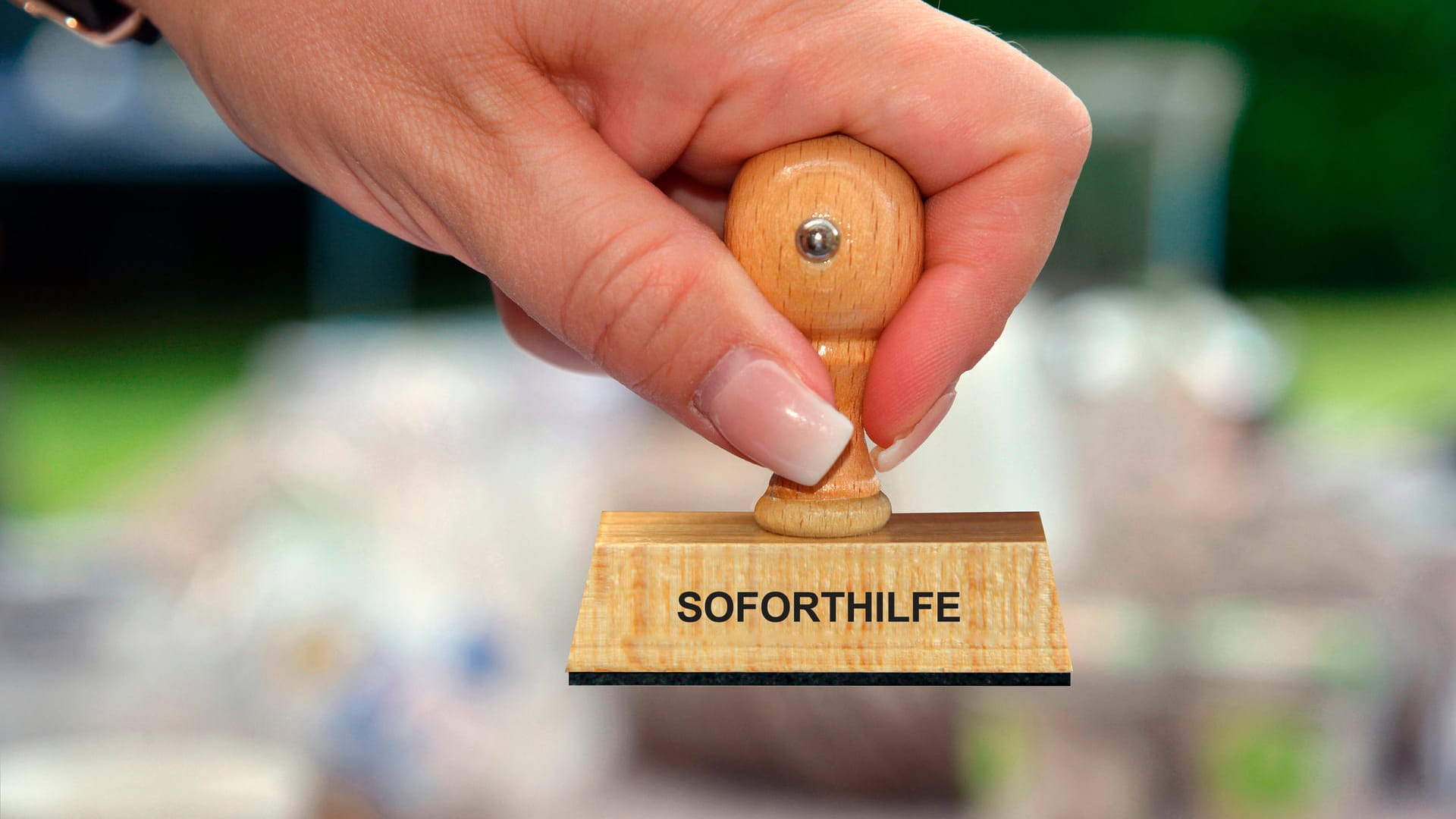 Eine Frau hält einen Stempel in der Hand mit der Aufschrift "Soforthilfe" (Symbolbild): Einige Wolfsburger warten in der Corona-Krise noch immer auf Fördermittel.