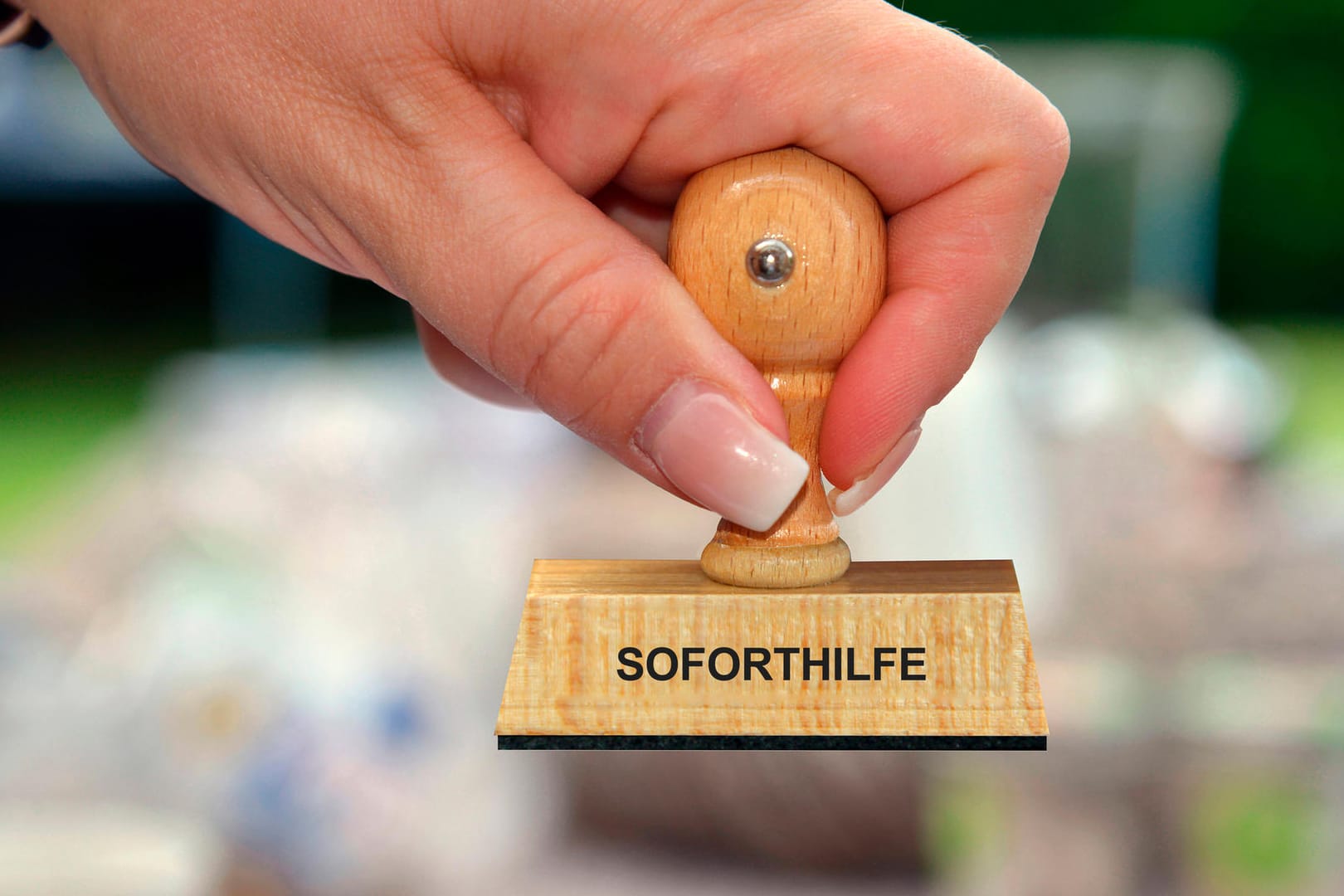 Eine Frau hält einen Stempel in der Hand mit der Aufschrift "Soforthilfe" (Symbolbild): Einige Wolfsburger warten in der Corona-Krise noch immer auf Fördermittel.