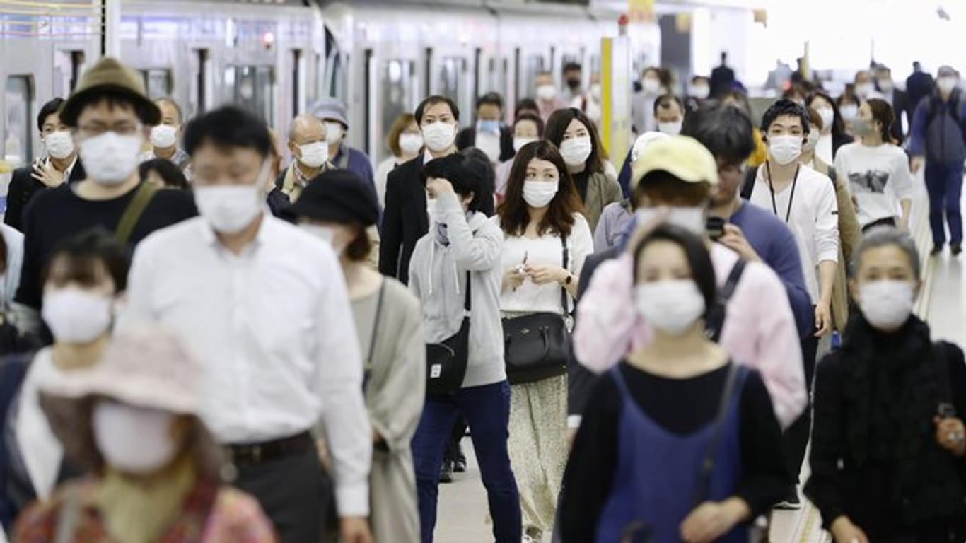 Pendler mit Gesichtsmasken am Bahnhof Fukuoka im Südwesten Japans.
