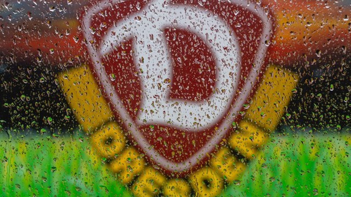 Das Logo von SG Dynamo Dresden ist hinter Regentropfen an einer Autoscheibe zu sehen: Der Verein fordert die Partie gegen Arminia Bielefeld zu verschieben.
