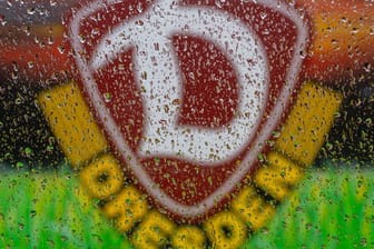 Das Logo von SG Dynamo Dresden ist hinter Regentropfen an einer Autoscheibe zu sehen: Der Verein fordert die Partie gegen Arminia Bielefeld zu verschieben.