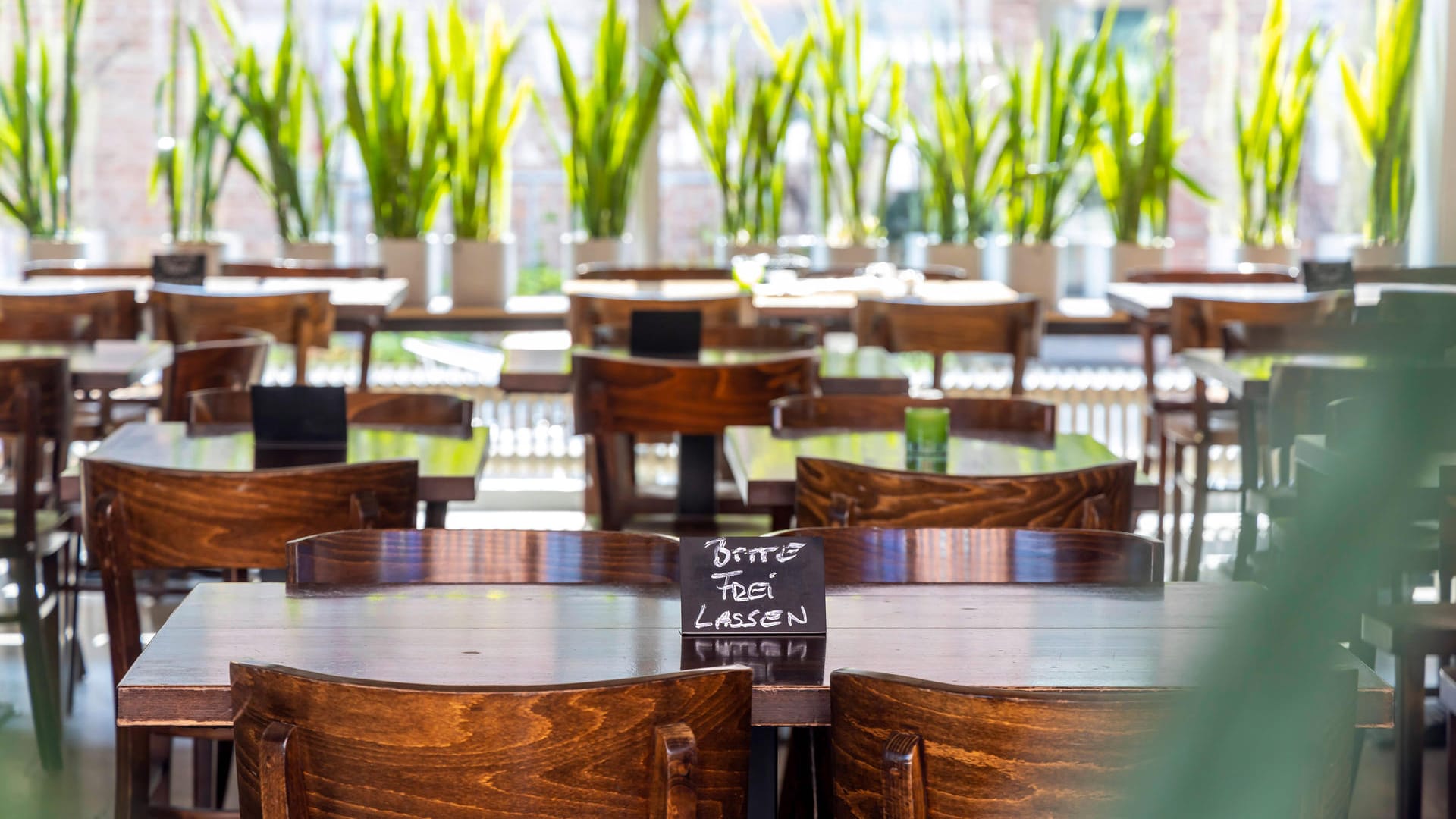 Auf einem Tisch steht ein Schild "Bitte frei lassen": Für Restauranttische gilt ein Mindestabstand von eineinhalb Metern.