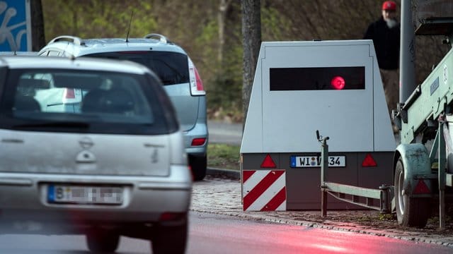 Ein Auto fährt an einem mobilen Blitzwagen, einem Geschwindigkeitsmessanhänger der Marke Votronic, vorbei. Ein Auto fährt an einem mobilen Blitzwagen, einem Geschwindigkeitsmessanhänger der Marke Votronic, vorbei.