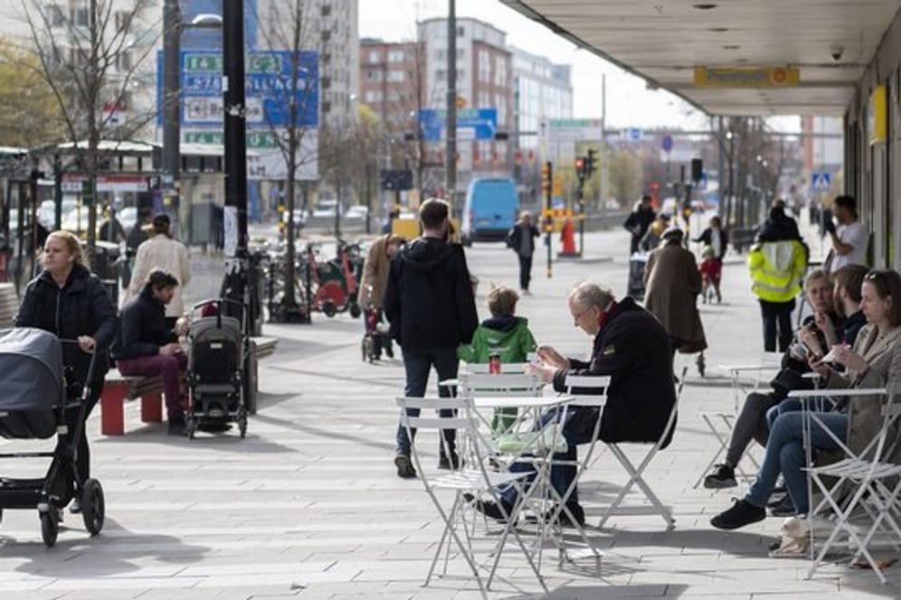 Menschen sitzen im Stadtzentrum von Stockholm vor einem Eiscafe.