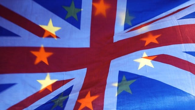 Die Sterne einer EU-Fahne scheinen durch eine britische Fahne hindurch. Die Sterne einer EU-Fahne scheinen durch eine britische Fahne hindurch.