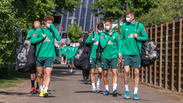 Die Bremer Profis mit Gesichtsmaske auf dem Weg zum Training. Werder steckt tief im Abstiegskampf – und muss nun noch auf einen Spieler verzichten, der in Quarantäne geschickt wurde.