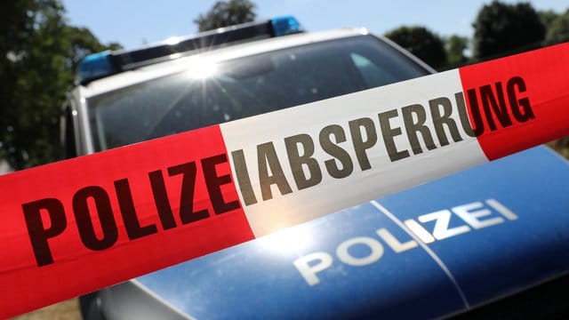 Eine Polizeiabsperrung hängt vor einem Polizeiauto