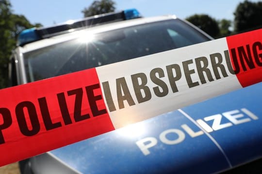 Eine Polizeiabsperrung hängt vor einem Polizeiauto