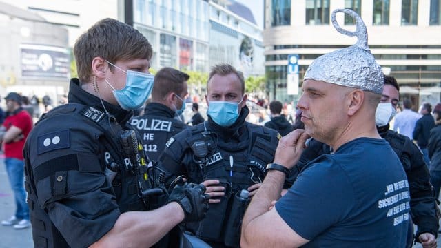 Polizisten erteilen einem Mann mit einem Alu-Hut einen Verweis Polizisten erteilen einem Mann mit einem Alu-Hut einen Verweis