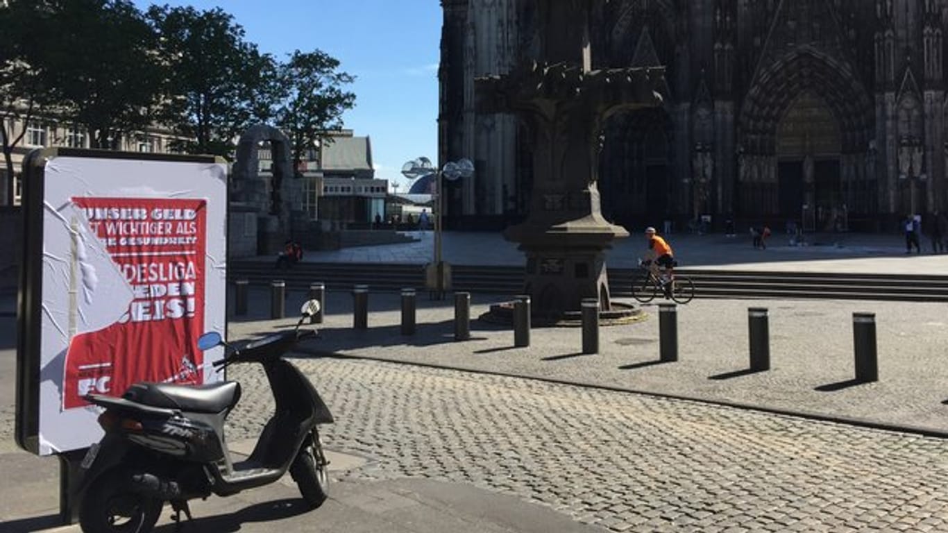Ein halb abgerissenes Plakat hängt an einer Werbefläche vor dem Kölner Dom.