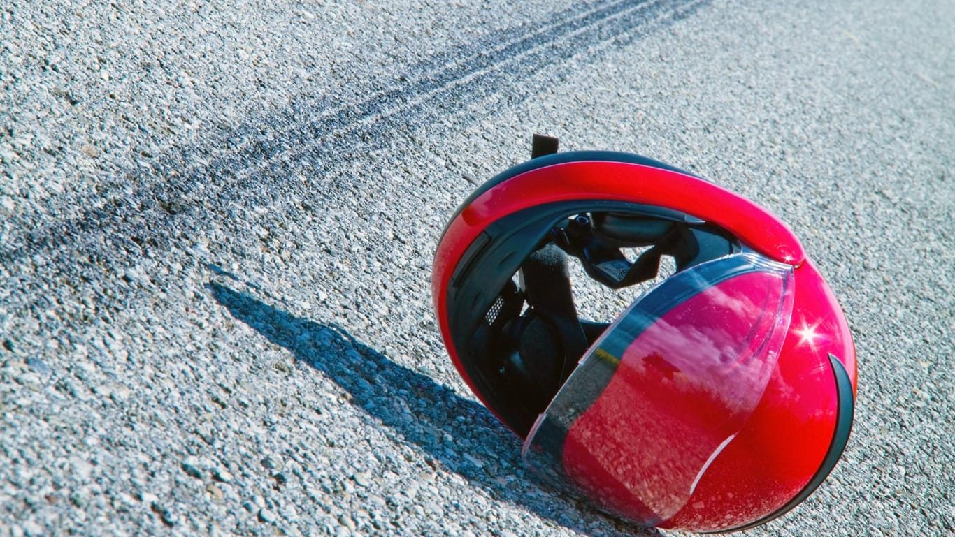 Der Helm eines Motorradfahrers liegt nach einem Unfall auf der Straße: Trotz Reanimationsmaßnahmen verstarb der Mann noch vor Ort. (Symbolbild)