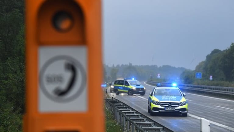 Polizeiautos mit eingeschaltetem Blaulicht stehen nach einem Unfall in der Nähe einer Notrufsäule (Symbolbild): Kölner Beamte konnten einen Mann auf der A57 nach einer riskanten Fahrt stoppen.
