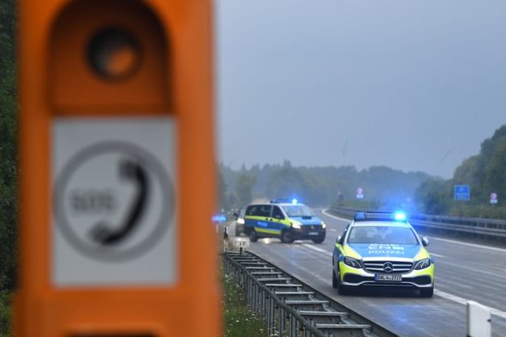 Polizeiautos mit eingeschaltetem Blaulicht stehen nach einem Unfall in der Nähe einer Notrufsäule (Symbolbild): Kölner Beamte konnten einen Mann auf der A57 nach einer riskanten Fahrt stoppen.