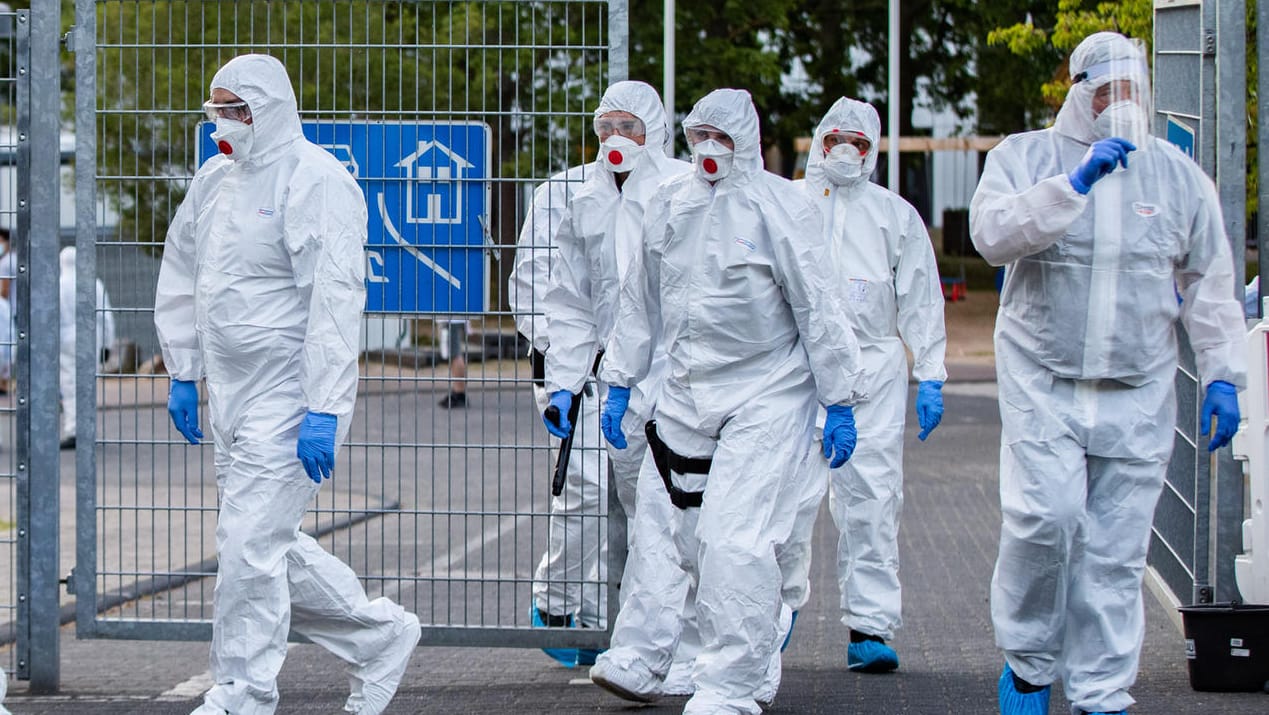 Polizisten in Schutzanzügen betreten ein Flüchtlingsheim in Sankt Augustin: Hier wurden am Wochenende 70 Corona-Infektionen festgestellt.