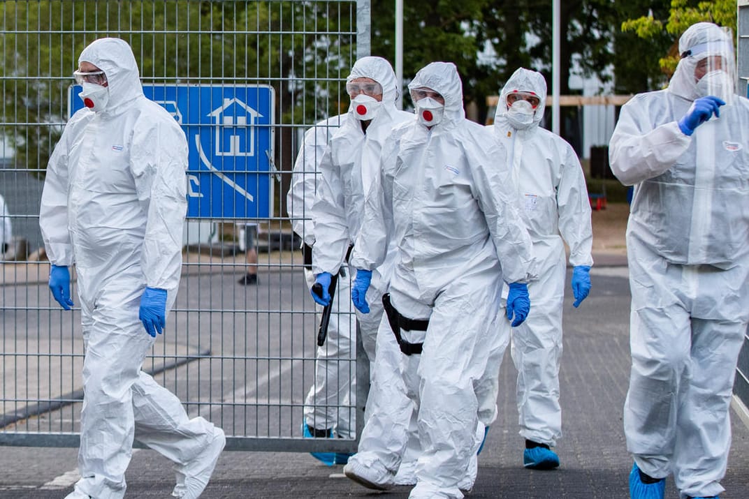 Polizisten in Schutzanzügen betreten ein Flüchtlingsheim in Sankt Augustin: Hier wurden am Wochenende 70 Corona-Infektionen festgestellt.