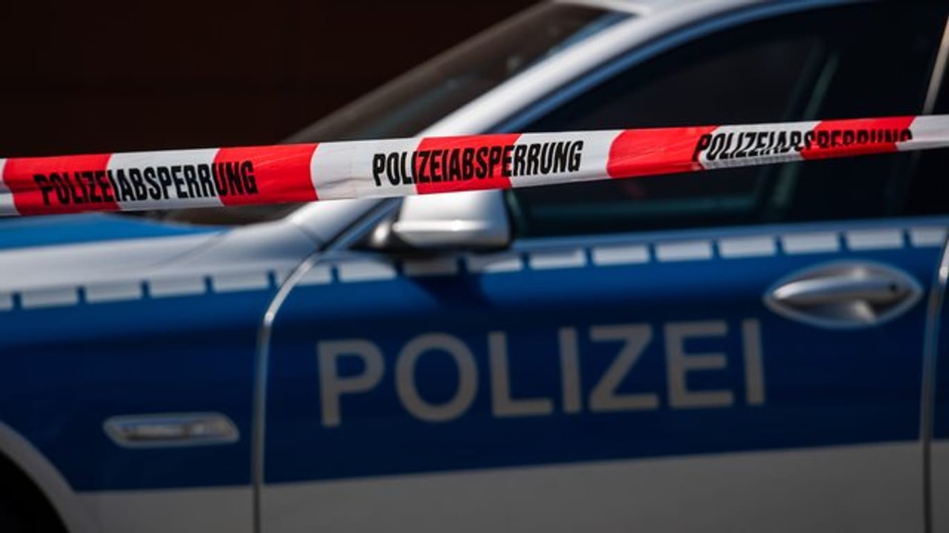 Ein Polizeiauto steht hinter einer Polizeiabsperrung (Symbolbild): In Frankfurt hat die Polizei mehrere Wohnungen durchsucht und Waffen und Drogen gefunden.