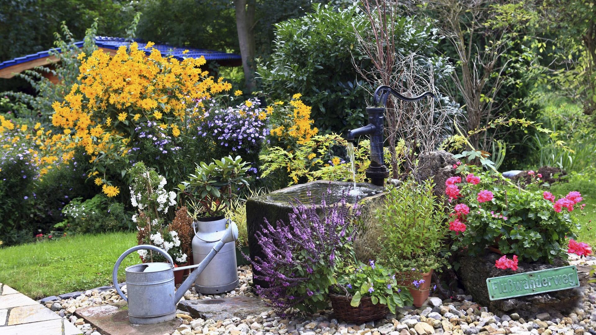 Gartenaccessoire: Eine Schwengelpumpe wirkt auch als Dekoration inmitten bunter Pflanzenkübel.