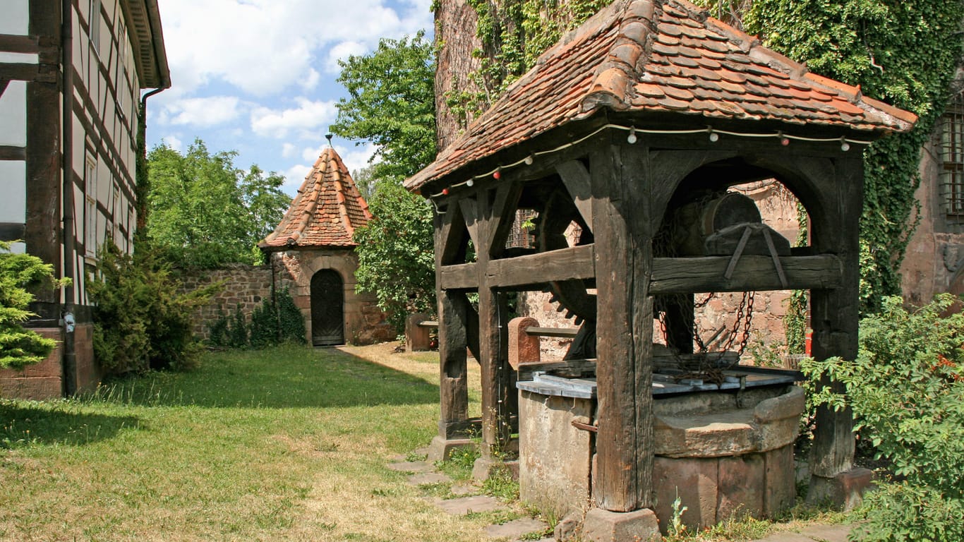 Historischer Schachtbrunnen: Ein hölzernes Brunnenhaus mit altem Räderwerk, errichtet um 1600, diente zur Wasserversorgung der Burganlage im hessischen Schlitz.