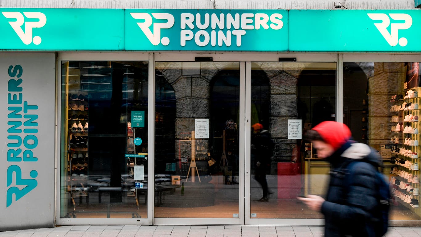 Ein Mann läuft vor dem geschlossenen Eingang eines Kaufhauses der Sportartikel-Handelskette Runners Point in der Innenstadt von Hamburg entlang.