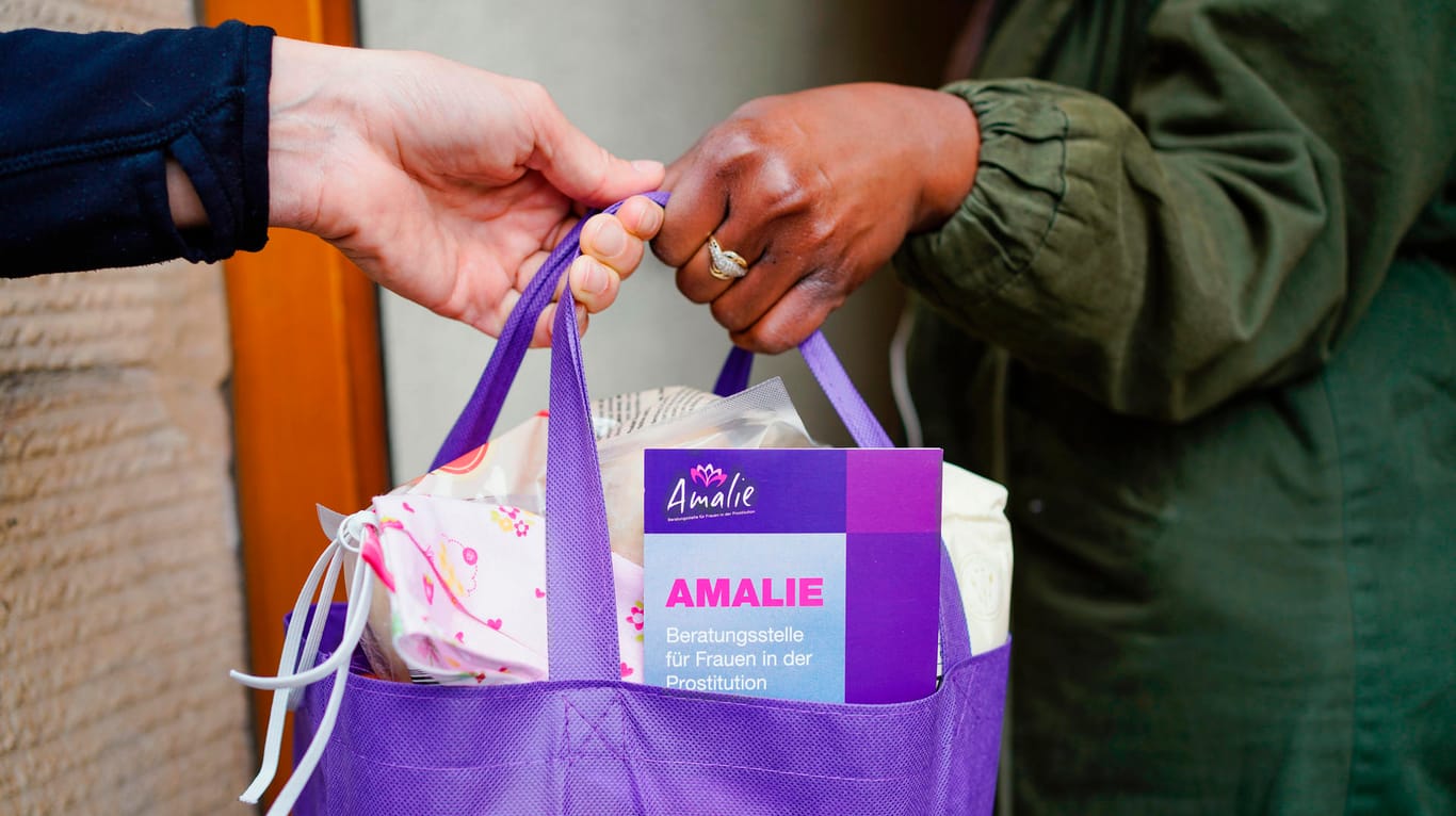 Mannheim: Eine Prostituierte nimmt an einer Haustür eine mit Lebensmitteln und Informationsmaterial gepackte Tasche der Beratungsstelle "Amalie" entgegen.