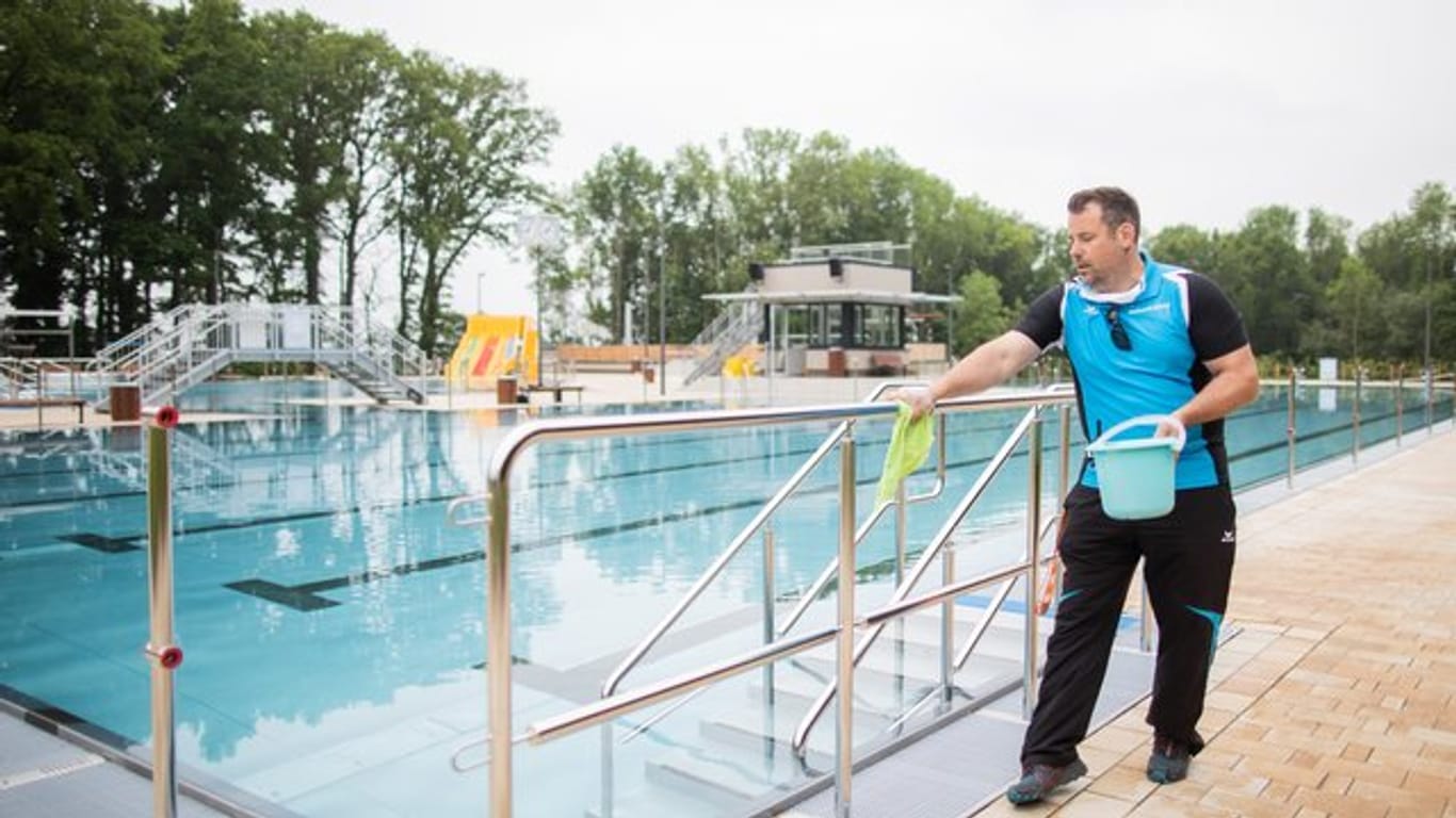Freibad: Der Schwimmmeister Björn Bendias in Ochtrup desinfiziert zwischen zwei Schwimmzeiten die Handläufe neben dem Schwimmbecken.