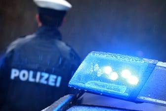 Ein Polizist steht vor einem Streifenwagen: In Hagen hat ein falscher Polizist erneut zugeschlagen.