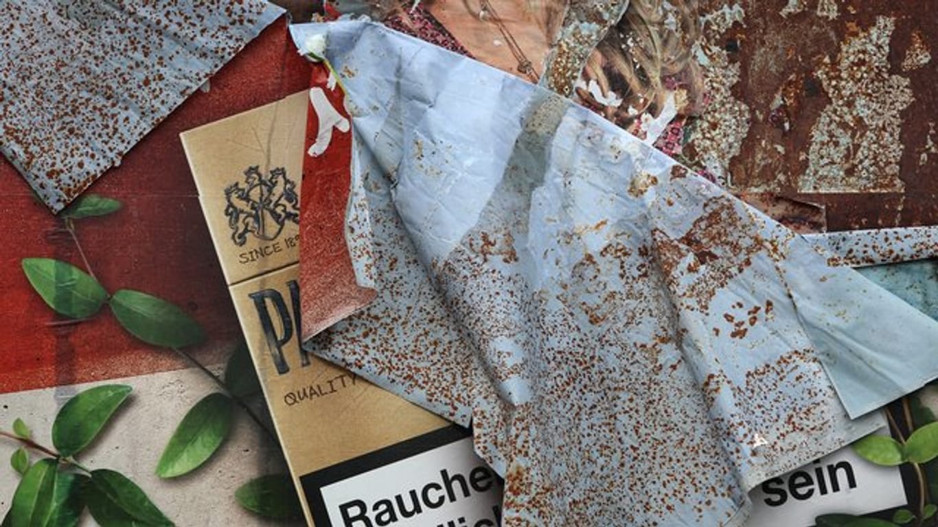 Ein Plakat mit Zigarettenwerbung löst sich von einer Plakatwand.