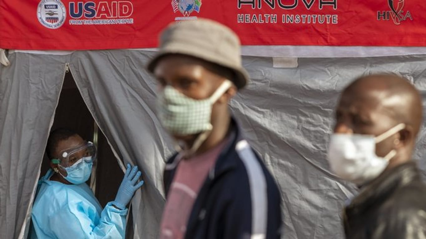 Menschen stehen in Johannesburg vor einem Zelt an, um sich auf eine Infektion mit dem Coronavirus testen zu lassen.