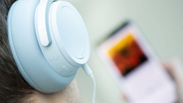 Ein junger Mann hört auf seinem Smartphone einen Podcast. Ein junger Mann hört auf seinem Smartphone einen Podcast.