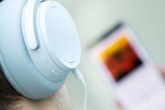 Ein junger Mann hört auf seinem Smartphone einen Podcast.