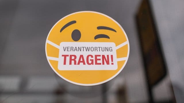 Ein Smiley-Aufkleber "mit Mundschutz" an der Scheibe einer Straßenbahn. Ein Smiley-Aufkleber "mit Mundschutz" an der Scheibe einer Straßenbahn.