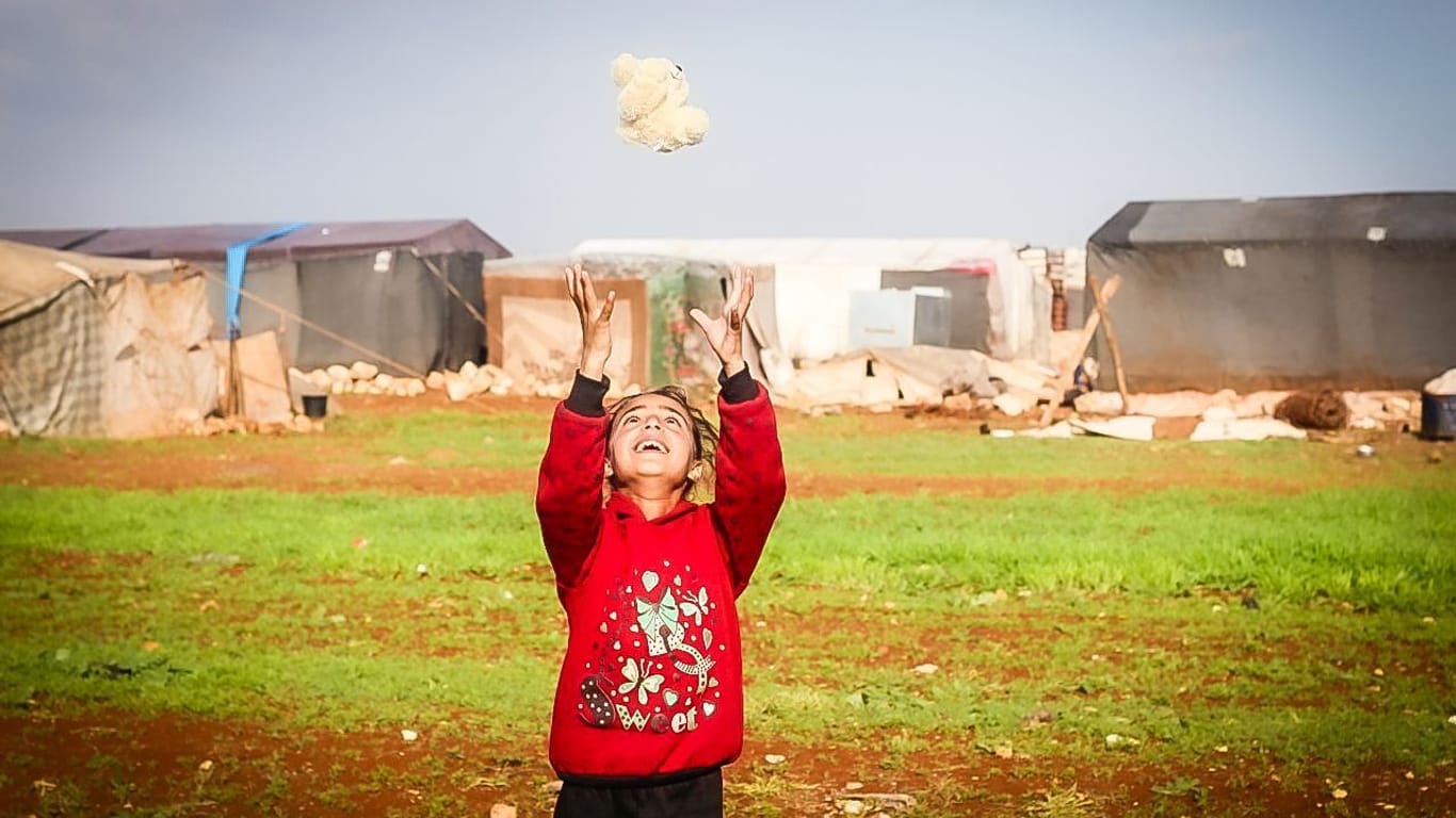 Ein Kind in einem Flüchtlingslager in Idlib freut sich über ein Kuscheltier.