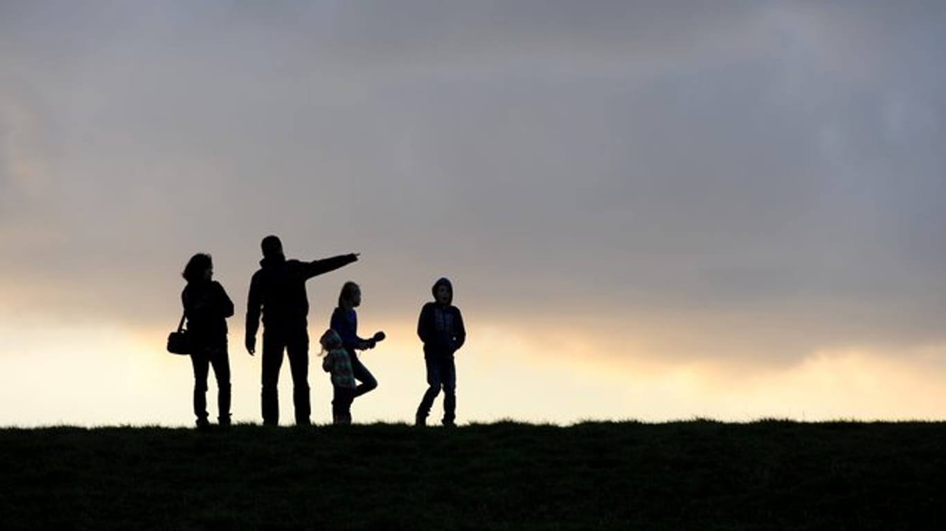 Eine Familie beim Spaziergang unterm abendlichen Wolkenhimmel.