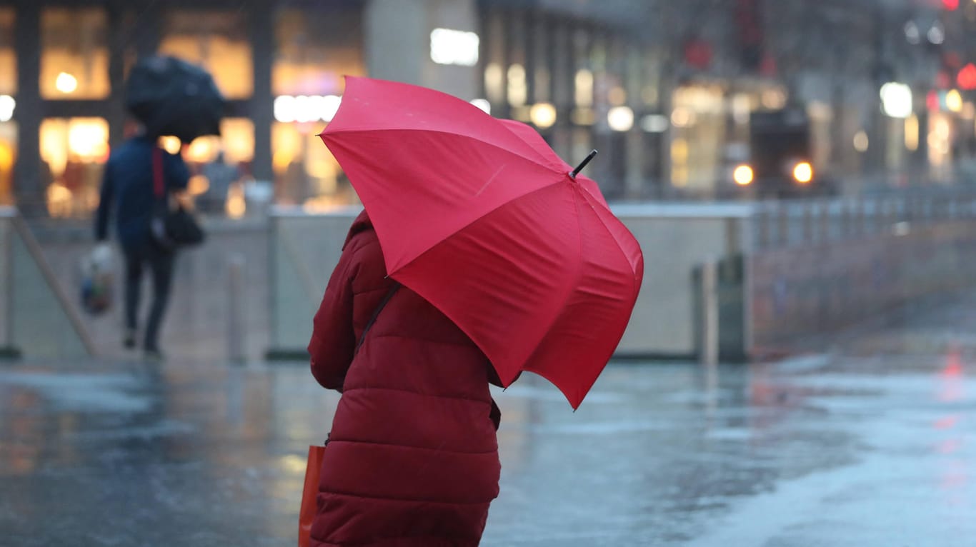 Eine Frau kämpft mit ihrem Regenschirm: Das Wetter am Wochenende wird ungemütlich (Symbolbild).