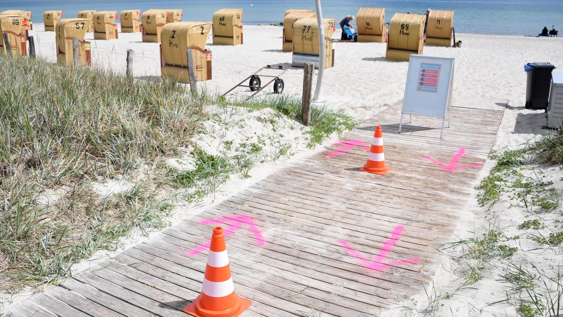 Haffkrug (Schleswig-Holstein,: Auf den Boden gesprühte Pfeile und Pylonen regeln den Zugang zum Strand an der Ostsee.