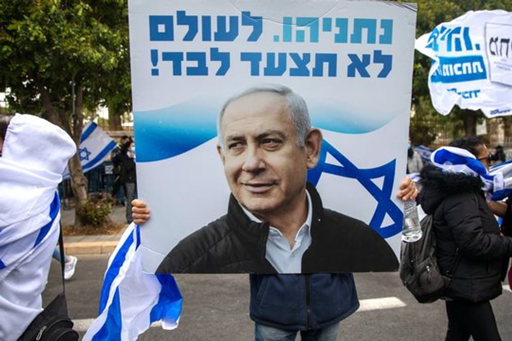 Anhänger von Ministerpräsident Netanjahu schwenken Fahnen und halten Plakate vor seiner Residenz in Jerusalem hoch.