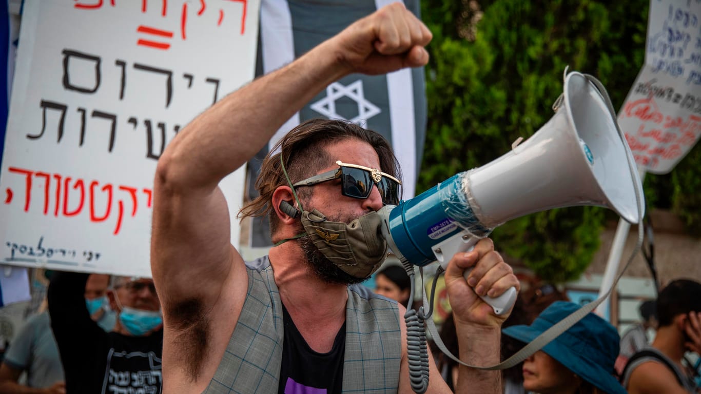 Ein Demonstrant schreit in ein Megafon bei einer Demonstration gegen die Bildung der neuen israelischen Regierung.