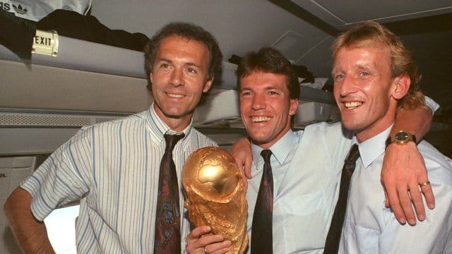 Auf dem Rückflug von Rom präsentieren DFB-Teamchef Franz Beckenbauer (l), Kapitän Lothar Matthäus (M) und Andreas Brehme den WM-Pokal. Auf dem Rückflug von Rom präsentieren DFB-Teamchef Franz Beckenbauer (l), Kapitän Lothar Matthäus (M) und Andreas Brehme den WM-Pokal.