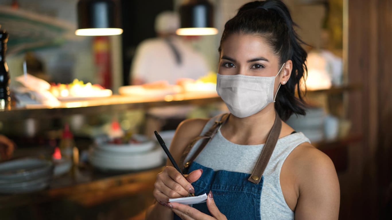 Kellnerin mit Maske: Nach wochenlangen Corona-Maßnahmen werden die Regeln für Restaurants und Cafés gelockert.