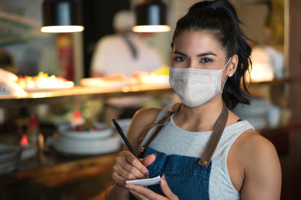 Kellnerin mit Maske: Nach wochenlangen Corona-Maßnahmen werden die Regeln für Restaurants und Cafés gelockert.